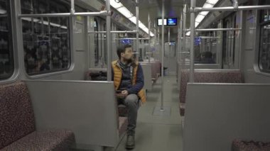 Adam Berlin, Almanya 'da metroya biniyor ve akıllı telefon kullanıyor. Banliyö treninde akıllı telefonu olan bir erkek. Berlin metrosunda internette internette sörf yapan bir yolcu. Fahrgast in der U-Bahn in Berlin, Deutschland. 
