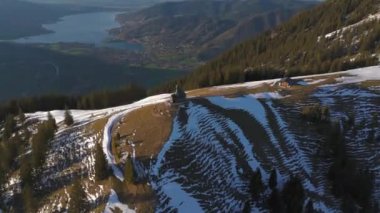 Kapelle Heilig Kreuz Rottach-Egern Tegernsee. Wallbergkapelle, Tegernsee Gölü 'ne tepeden bakan Wallberg Dağı ve güneşli bahar havasında gün batımında karla kaplı dağ sıraları. Alplerin zirvesindeki şapel. 