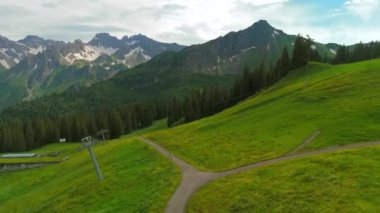 Yazın Alpler 'de kayak merkezinde bisiklet süren hava manzaralı bisikletçi. Bisikletçi Almanya 'nın Bavyera dağlarındaki dağ tatil beldesinde çakıllı bisikletle seyahat ediyor. Alp yamaçlarında bisiklet gezileri 