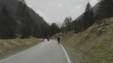 Erkek bisikletçi, güneşli bir baharda Avusturya dağlarında asfalt bir yolda bisiklet sürüyor. Alplerde yol bisikleti. Tyrol, Avusturya 'da arabaları ve motosikletçileri olan bir yolda bisiklet sürüyor. 