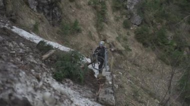 Bisikletçi dağlarda çığ üzerinden bisiklet çekiyor. Bisikletçi engelin içinde sıkıştı ve bisikletini elinde bisikletle bir buz kaydırağının içinden geçiriyor. Alplerdeki bisiklet rotasında çığ. 