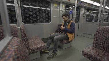 Adam Berlin, Almanya 'da metroya biniyor ve akıllı telefon kullanıyor. Banliyö treninde akıllı telefonu olan bir erkek. Berlin metrosunda internette internette sörf yapan bir yolcu. Fahrgast in der U-Bahn in Berlin, Deutschland. 