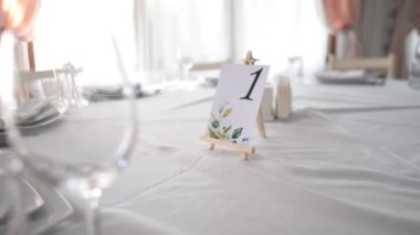 Masa takımı ile servis edilen restoranda masa numarası insan ve yiyecek olmadan festival etkinliği için hazırlandı. Düğün masası dekore edildi. Misafir masası numarası. Restorandaki düğün masası. Düğün için. Ziyafet.. 