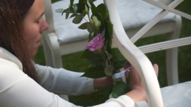 Kadın dekoratör arka bahçede yapılacak bir düğün için beyaz sandalyeler dekore ediyor. Düğün ajansı çalışanı dışarıdaki düğün için sokak mobilyalarını dekore ediyor. Düğün mobilyaları süslemesi. 
