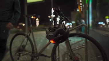 Tıbbi maskeli bir bisikletçi mağazadan çıkar, park halindeki bisiklete yürür ellerini dezenfektanla tedavi eder, bisiklet kaskı takar ve şehirde akşam üstü kırmızı ışık yakar. Tema hijyen ve koruma. 