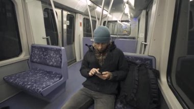 Hamburg 'da metroda seyahat eden mavi koltukta oturan ve kışlık kıyafetler giymiş akıllı telefon kullanan bir adam. Hamburg metro banliyösü işe gidip gelirken internette geziniyor. Hamburger U-Bahn. 