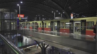 25 Aralık 2023. Berlin, Almanya. Berlin ana tren istasyonu. Akşamları içeride. Banliyö seviyesinde sarı renkli trenler ve yolcular var. Berlin Hauptbahnhof am Abend und Zug S-Bahn. 