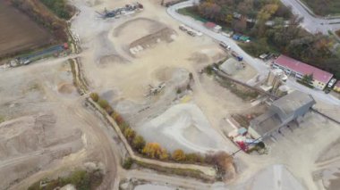 Almanya 'da endüstriyel bölgede çalışan kum ocaklarının hava görüntüsü. Yoğun makineler, sonbahar sisi ile örtülmüş, genişleyen kumlu arazide aktif bir çalışma alanı atmosferinin altını çizerek çalışır.. 