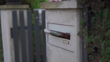 Alman evinin dışındaki posta kutusundan yuvarlanmış gazete çubukları. Sabah ışığı ön bahçeyi aydınlatıyor, sakin Alman mahallesindeki günlük hayata bir göz atıyor. Geleneksel, basit ve klasik. 