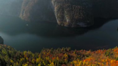 Konigssee, Bavyera 'nın en güzel gölü sonbaharda güneşli gökyüzünün altında parlar. Elektrikli tekneler kristal berrak sularda süzülürken aynı zamanda turistler için dingin çevre dostu deneyimler sunuyor.