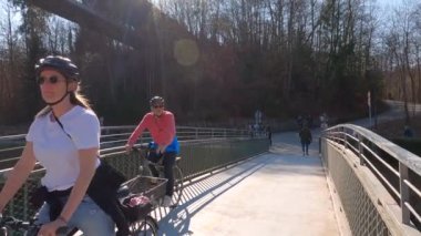 22 Mart 2022. Münih, Almanya. Bisikletçiler ilkbaharda Münih 'te güneşli ve ılık bir havada Isar Nehri boyunca bisiklet yolu üzerinde gezerler. Avrupa 'da nehir boyunca şehir turuna çıkan bisikletçiler. Aktif boş zaman. 