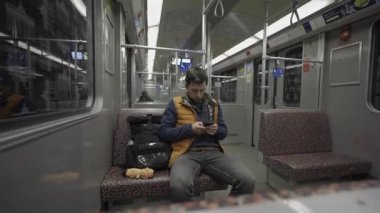 Adam Berlin, Almanya 'da metroya biniyor ve akıllı telefon kullanıyor. Banliyö treninde akıllı telefonu olan bir erkek. Berlin metrosunda internette internette sörf yapan bir yolcu. Fahrgast in der U-Bahn in Berlin, Deutschland. 
