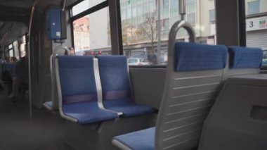Almanya, Münih 'te içi boş koltuklar sergileyen bir tramvayın içinde. Tramvay koltuklarının tasarımı ve dışarıdaki hareketli şehir manzarası, şehirde toplu taşıma deneyimini vurguluyor.. 