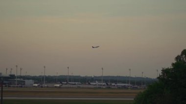Almanya 'daki Münih havaalanından gün batımında kalkan uçaklar. Akşam havaalanı pistinde uçan yolcu uçağı. Jet turuncu bir günbatımına doğru uçuyor. Flugzeug startet am Flughafen Munchen. 