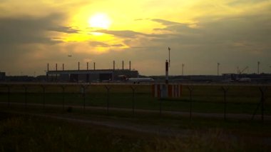 Almanya 'daki Münih havaalanından gün batımında kalkan uçaklar. Akşam havaalanı pistinde uçan yolcu uçağı. Jet turuncu bir günbatımına doğru uçuyor. Flugzeug startet am Flughafen Munchen. 