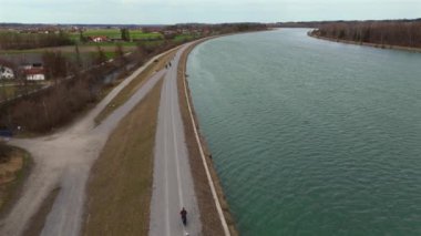 Bisikletçiler, Almanya 'nın Bavyera eyaletinde Rosenheim nehri boyunca bisiklet yolu üzerinde bisiklet sürerler. Ben Innradweg bei Rosenheim. Deutschland 'da geniş bir nehir boyunca çakıllı bisiklet yolu. Üst Bayern 'de döngü. 