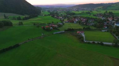 Yaz aylarında Alplerde gün batımı tren yolculuğunun insansız hava aracı görüntüsü. Almanya, Bavyera 'da seyahat eden demiryolu treninin hava görüntüsü. Deutschland, Bayern 'deki Schliersee' ye giden trenin en iyi manzarası. Demiryolu taşımacılığı. 