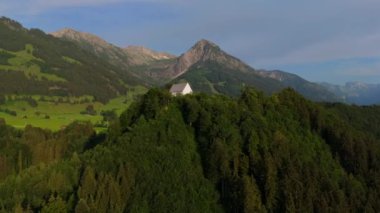 Schollanger burgkirche Fischen im Allgau, Bayern, Deutschland Luftaufnahme. Auwaldsee 'de. Dağa bakan nehir, dağlar ve Almanya 'nın Bavyera kentindeki Fischen' in tepesindeki güzel beyaz kilise.. 