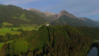 Schollanger burgkirche Fischen im Allgau, Bayern, Deutschland Luftaufnahme. Auwaldsee 'de. Dağa bakan nehir, dağlar ve Almanya 'nın Bavyera kentindeki Fischen' in tepesindeki güzel beyaz kilise.. 
