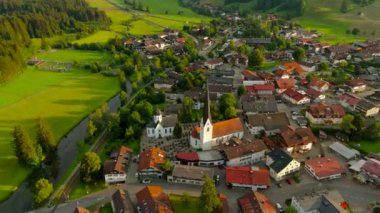 Almanya, Bavyera, Fischen im Allgaeu 'deki St. Verena büyüleyici bir Alp köyüdür. Yukarıdan bakıldığında, yazın günbatımında tarihi kilise ve kırsal hava manzarasının nefes kesici görüntülerini sunuyor.. 