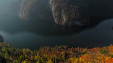 Konigssee, Bavyera 'nın en güzel gölü sonbaharda güneşli gökyüzünün altında parlar. Elektrikli tekneler kristal berrak sularda süzülürken aynı zamanda turistler için dingin çevre dostu deneyimler sunuyor.