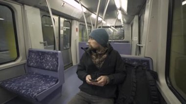 Hamburg 'da metroda seyahat eden mavi koltukta oturan ve kışlık kıyafetler giymiş akıllı telefon kullanan bir adam. Hamburg metro banliyösü işe gidip gelirken internette geziniyor. Hamburger U-Bahn. 