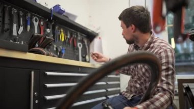 Bisiklet tamircisi, bisiklet atölyesinde tekerlek ve çakıl bisikletinin merkezini tamir ediyor. Bisiklet tamircisinde çalışan bisikletçi çakıl merkezini tamir ediyor. Bisiklet onarımı, servis ve bakım. 