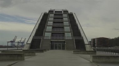 Hamburg, Almanya. Hamburg 'daki modern mimari Dockland ofis binası. Ziyaretçiler için merdiven erişimi olan rıhtım binası ve Elbe Nehri 'nin liman ve kıyısının manzarası. 