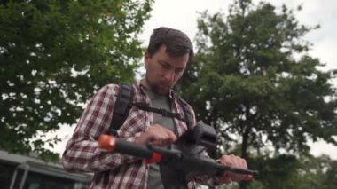 Adam şehirde elektrikli scooter kiralamak için akıllı telefon kullanıyor. Genç adam e-scooter 'ın parasını cep telefonuyla internet üzerinden ödüyor. Elektrikli araç kiralama teması. Kentsel çevre dostu ulaşım. 