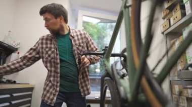 Bisiklet tamircisi atölyedeki bisiklet gidonu şeridini değiştiriyor. Bisiklet tamiri ve hizmet kavramı. Bisiklet teknisyeni gidona bant yapıştırıyor. Tamircide çalışan bisiklet tamircisi.. 