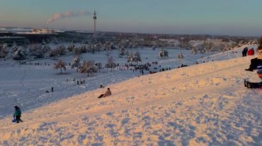 3 Aralık 2023. Münih, Almanya, Riemer Park, Messestadt. Riem parkındaki Toboggan tepesi ve gözlem güvertesi tepesi. Güneşli kış havasında Münih 'te bir parkta karlı dağda kayak yapan mutlu insanlar.. 