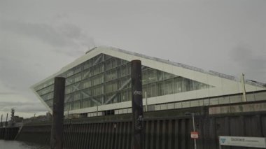 Hamburg, Almanya. Hamburg 'daki modern mimari Dockland ofis binası. Ziyaretçiler için merdiven erişimi olan rıhtım binası ve Elbe Nehri 'nin liman ve kıyısının manzarası. 