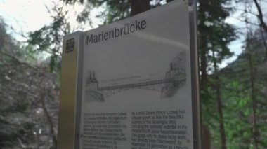 30 Mart 2024, Fussen, Almanya. Marienbrucke girişi ya da Kraliçe Marys Köprüsü yaya köprüsü uçurum üzerindeki Neuschwanstein Kalesi manzaralı. İnsanlar Neuschwanstein 'e yüksek köprüden bakıyor 