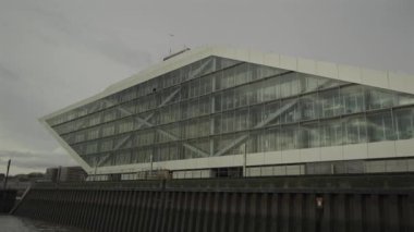 Hamburg, Almanya. Hamburg 'daki modern mimari Dockland ofis binası. Ziyaretçiler için merdiven erişimi olan rıhtım binası ve Elbe Nehri 'nin liman ve kıyısının manzarası. 