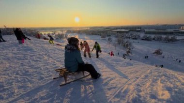 3 Aralık 2023. Münih, Almanya, Riemer Park, Messestadt. Riem parkındaki Toboggan tepesi ve gözlem güvertesi tepesi. Güneşli kış havasında Münih 'te bir parkta karlı dağda kayak yapan mutlu insanlar.. 