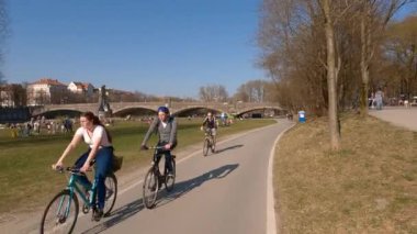 22 Mart 2022. Münih, Almanya. Bisikletçiler ilkbaharda Münih 'te güneşli ve ılık bir havada Isar Nehri boyunca bisiklet yolu üzerinde gezerler. Avrupa 'da nehir boyunca şehir turuna çıkan bisikletçiler. Aktif boş zaman. 