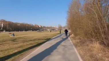 22 Mart 2022. Münih, Almanya. Bisikletçiler ilkbaharda Münih 'te güneşli ve ılık bir havada Isar Nehri boyunca bisiklet yolu üzerinde gezerler. Avrupa 'da nehir boyunca şehir turuna çıkan bisikletçiler. Aktif boş zaman. 