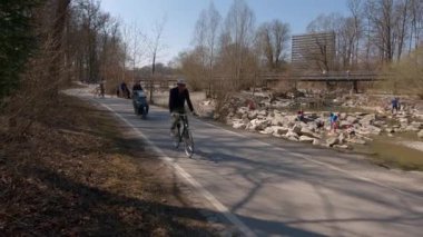 22 Mart 2022. Münih, Almanya. Bisikletçiler ilkbaharda Münih 'te güneşli ve ılık bir havada Isar Nehri boyunca bisiklet yolu üzerinde gezerler. Avrupa 'da nehir boyunca şehir turuna çıkan bisikletçiler. Aktif boş zaman. 