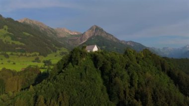 Schollanger burgkirche Fischen im Allgau, Bayern, Deutschland Luftaufnahme. Auwaldsee 'de. Dağa bakan nehir, dağlar ve Almanya 'nın Bavyera kentindeki Fischen' in tepesindeki güzel beyaz kilise.. 
