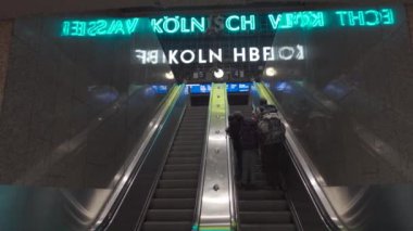 31 Temmuz 2024. Köln, Almanya. Koeln Hauptbahnhof 'da canlı bir akşam sahnesi yürüyen merdivenli, ışıklı tabelalı, modern mimari, Almanya' daki anahtar taşıma merkezi.. 
