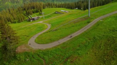 Yazın Alpler 'de kayak merkezinde bisiklet süren hava manzaralı bisikletçi. Bisikletçi Almanya 'nın Bavyera dağlarındaki dağ tatil beldesinde çakıllı bisikletle seyahat ediyor. Alp yamaçlarında bisiklet gezileri 