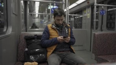Adam Berlin, Almanya 'da metroya biniyor ve akıllı telefon kullanıyor. Banliyö treninde akıllı telefonu olan bir erkek. Berlin metrosunda internette internette sörf yapan bir yolcu. Fahrgast in der U-Bahn in Berlin, Deutschland. 