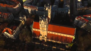 Kath. Pfarramt St. Maximilian Katholische Kirche Münih, Bayern, Deutschland Luftaufnahme 'de. Münih 'teki St. Maximilian' ın sonbahar renkleriyle çevrili, gün doğumunda ayırt edici kuleleri olan hava manzarası.. 