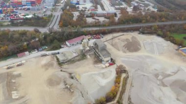 Almanya, Bavyera 'da, sisli sonbaharda endüstriyel bölgede aktif kum ocağının havadan görünüşü. Ağır makineler geniş bir alana yayılarak sanayi ve hammaddelerin katı, atmosferik manzarasını yaratıyor.. 