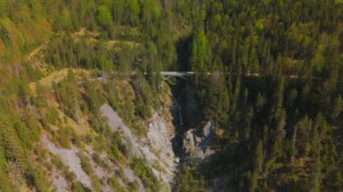 Luftaufnahme Schurpfen Wasserfall. Eğri şelale Schurpfen 'in hava manzarası ve Lenggries' deki Sylvensteinspeicher yakınlarında orman dağı ve kanyonla dolu bir köprü. İnsansız hava aracı görüntüsü düşüyor ve köprü. 