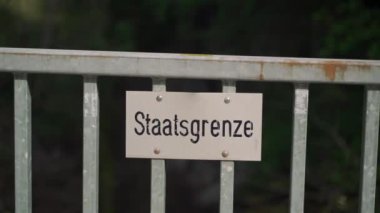 Schilder Grenze zwischen Deutschland ve Oesterreich. Tafel Staatsgrenze. Politische Grenze. Schild Grenzlinie zwischen Staatsgebieten. Çit Almanya 'da devlet sınırını işaret ediyor. Almanca Kenarlık Yazısı