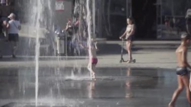 Ukraine, Odessa, August 25, 2021. Happy children playing and bathing in fountain in summer heat near sea beach in Odessa, Ukraine. Happy childhood. Kids excited and splashing water in the fountain. 