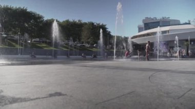 Ukraine, Odessa, August 25, 2021. Happy children playing and bathing in fountain in summer heat near sea beach in Odessa, Ukraine. Happy childhood. Kids excited and splashing water in the fountain. 