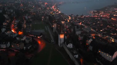 Musegg Wall ve dokuz kulesi geceleri İsviçre 'nin Lucerne kentindeki parlayan şehre bakıyor. Lucerne 'in ortaçağ savunması. Museggmauer Luzern und ihre neun Tuerme Luftaufnahme bei Nacht. 