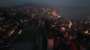 Musegg Wall ve dokuz kulesi geceleri İsviçre 'nin Lucerne kentindeki parlayan şehre bakıyor. Lucerne 'in ortaçağ savunması. Museggmauer Luzern und ihre neun Tuerme Luftaufnahme bei Nacht. 